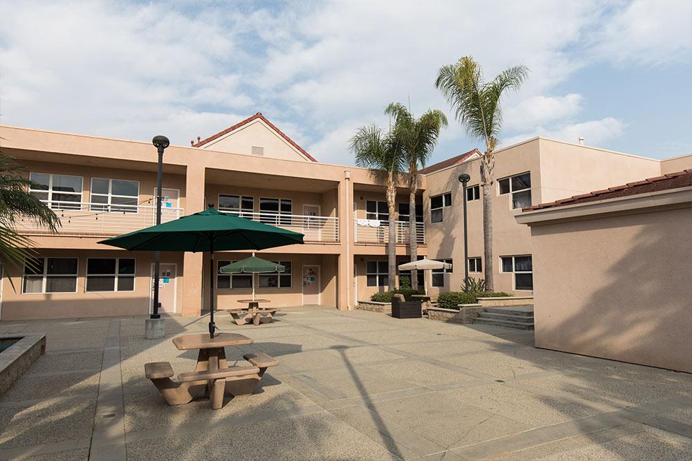 A courtyard of the 学生宿舍 with outdoor tables shaded by umbrellas